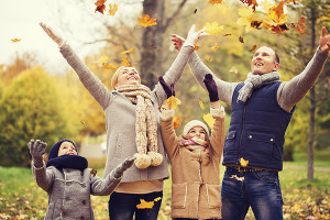 happy family playing with autumn leaves in park